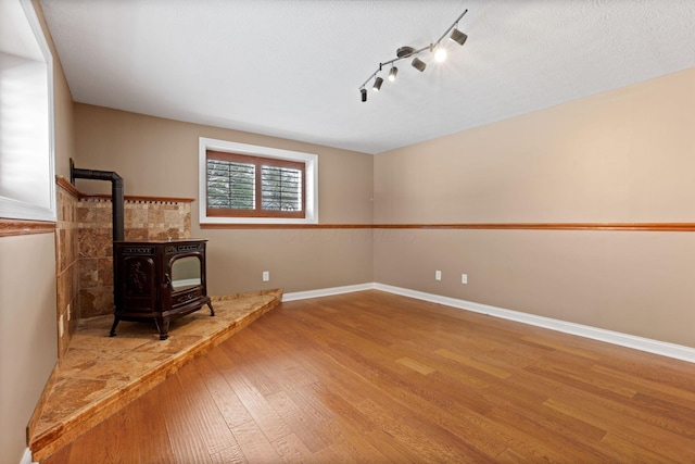 living room featuring a wood stove, hardwood / wood-style floors, and rail lighting