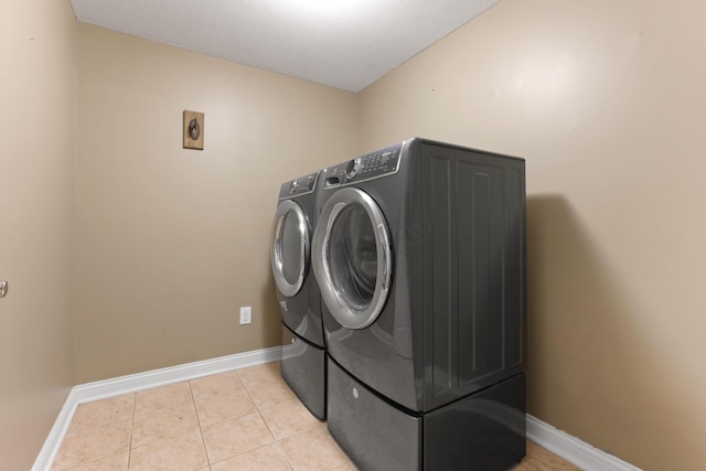 laundry room with light tile patterned floors, a textured ceiling, and washer and clothes dryer