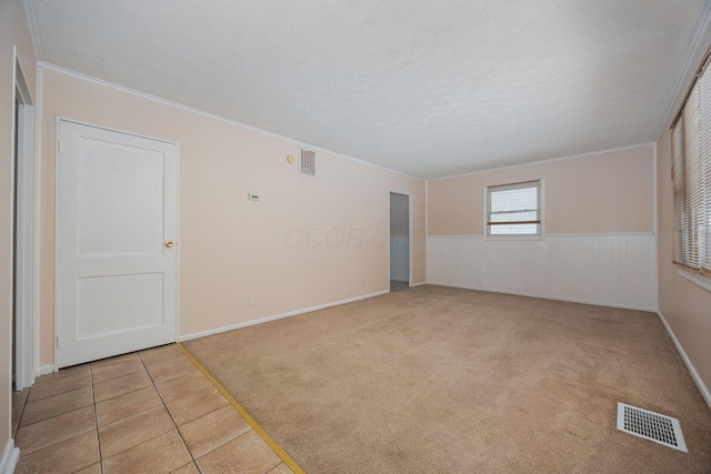 unfurnished room with light colored carpet, a textured ceiling, and ornamental molding