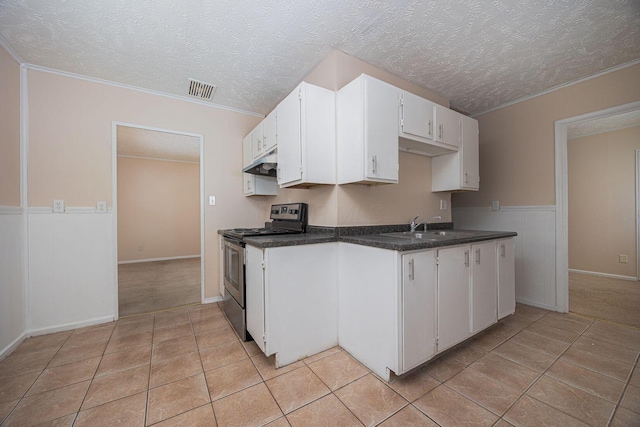 kitchen featuring stainless steel electric range oven, a textured ceiling, ornamental molding, light tile patterned flooring, and white cabinetry