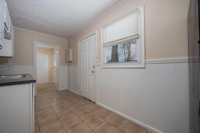 doorway featuring crown molding, sink, a textured ceiling, water heater, and light tile patterned flooring