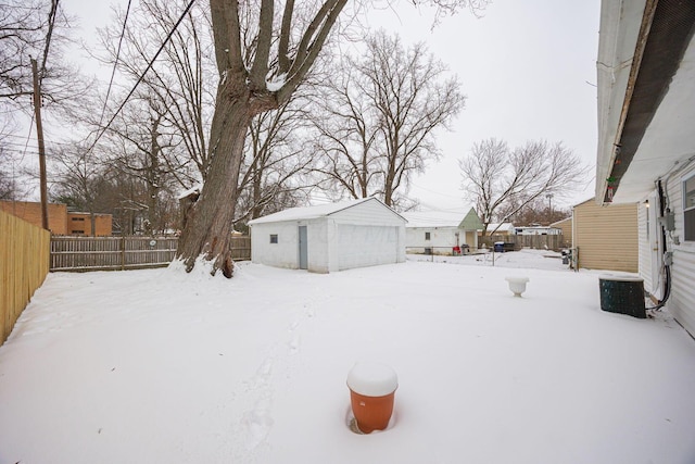 snowy yard with a garage, central AC unit, and an outdoor structure