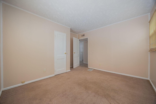 carpeted empty room with crown molding and a textured ceiling