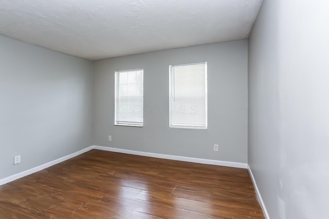 empty room featuring dark wood-type flooring and a textured ceiling