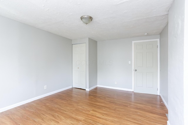 spare room featuring a textured ceiling and light wood-type flooring