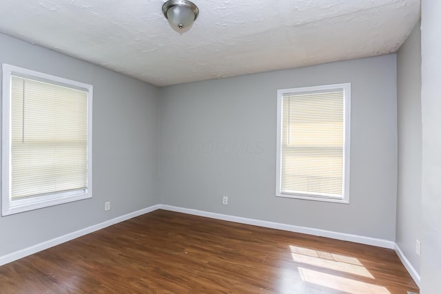 spare room with dark hardwood / wood-style flooring and a textured ceiling