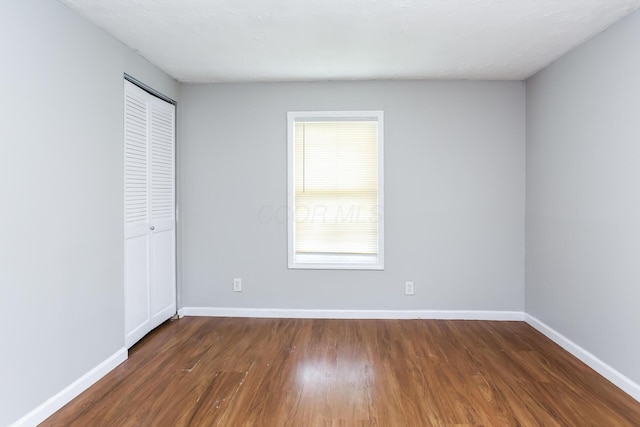 unfurnished bedroom featuring dark hardwood / wood-style flooring and a closet