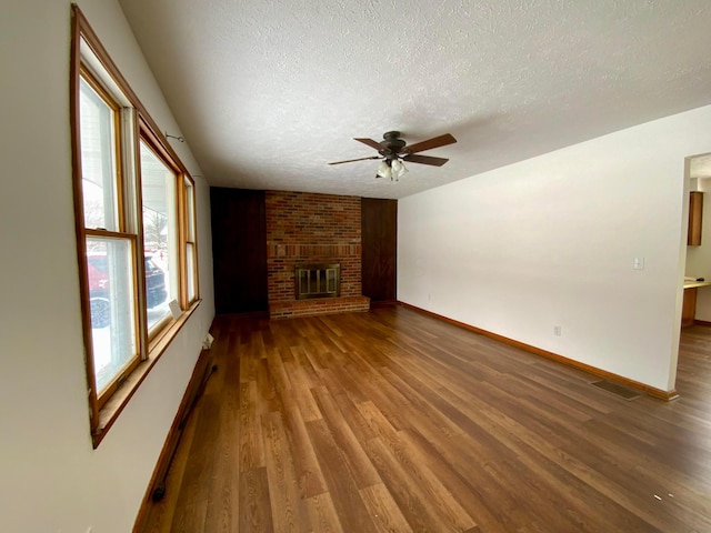 unfurnished living room featuring ceiling fan, a baseboard radiator, a textured ceiling, a fireplace, and hardwood / wood-style flooring