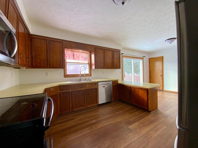 kitchen with appliances with stainless steel finishes, dark hardwood / wood-style floors, a wealth of natural light, and sink