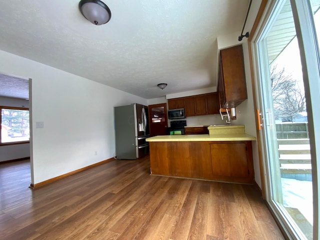 kitchen featuring kitchen peninsula, a textured ceiling, stainless steel appliances, and dark hardwood / wood-style floors