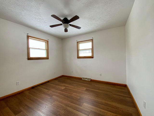 empty room featuring a textured ceiling, ceiling fan, and dark wood-type flooring