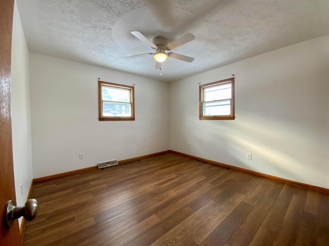 empty room with a textured ceiling, ceiling fan, and dark hardwood / wood-style floors