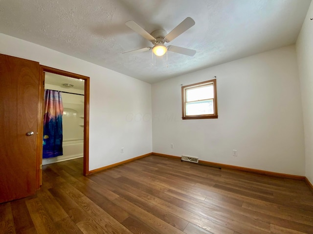 unfurnished bedroom featuring a textured ceiling, ceiling fan, and dark hardwood / wood-style floors