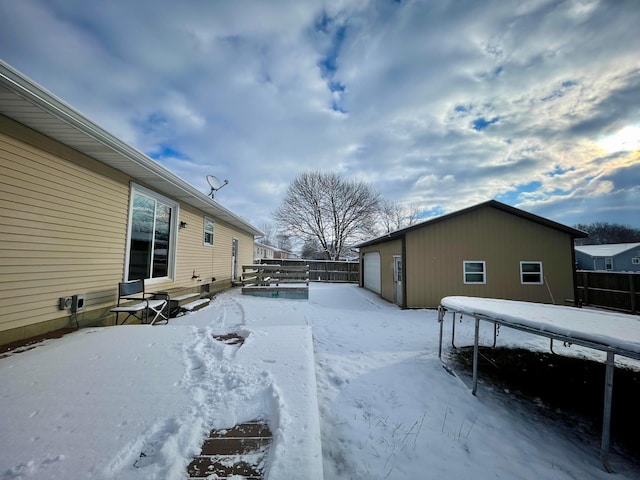 yard covered in snow featuring an outbuilding and a garage