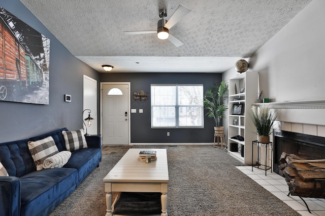 carpeted living room with a textured ceiling, ceiling fan, and a tiled fireplace