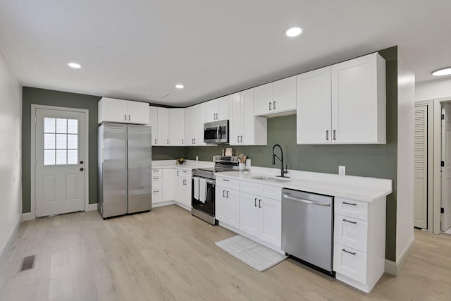 kitchen with white cabinetry, sink, light wood-type flooring, and appliances with stainless steel finishes