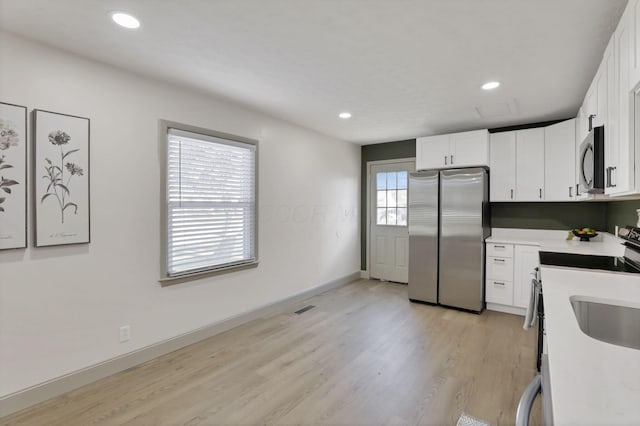 kitchen with white cabinets, light hardwood / wood-style floors, and stainless steel appliances