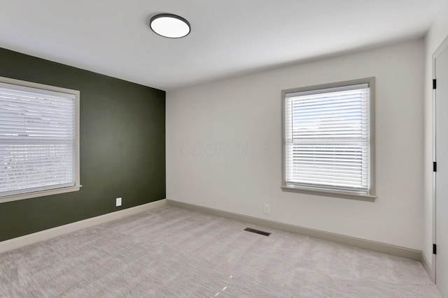 unfurnished room with light colored carpet and a wealth of natural light