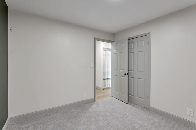 unfurnished bedroom with light carpet and a closet