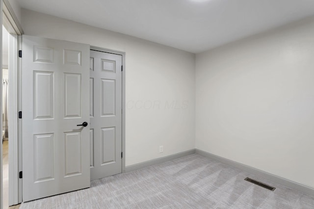 unfurnished bedroom featuring light carpet and a closet