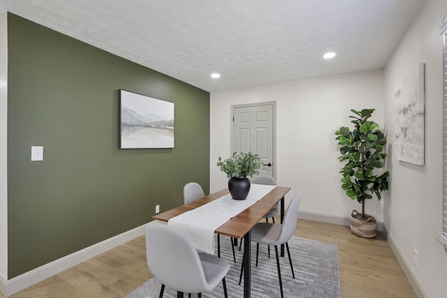 dining room with light hardwood / wood-style floors and a textured ceiling