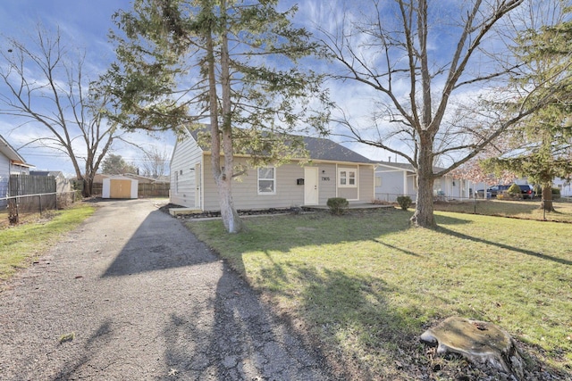 view of front of house featuring a front lawn and a storage shed