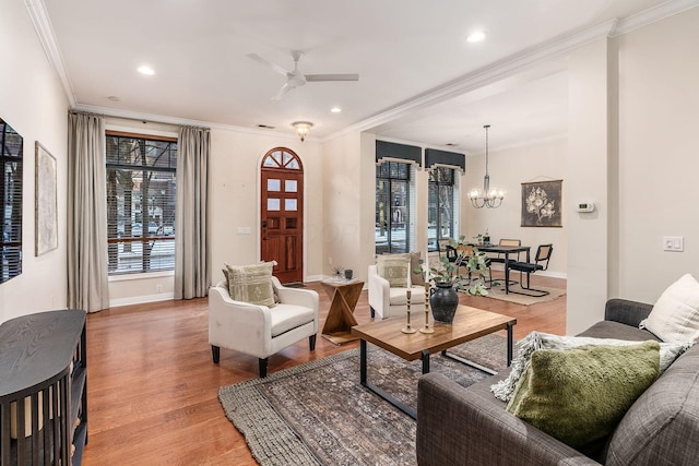 living room featuring ceiling fan with notable chandelier, ornamental molding, and wood-type flooring