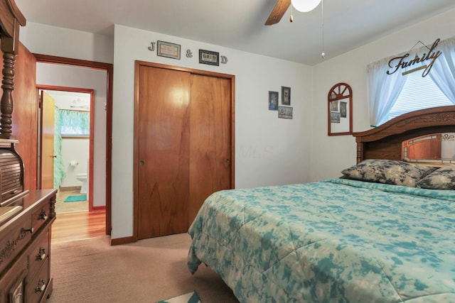 bedroom featuring a closet, ensuite bathroom, ceiling fan, and light colored carpet