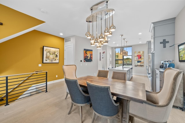 dining room featuring sink, a chandelier, and light wood-type flooring