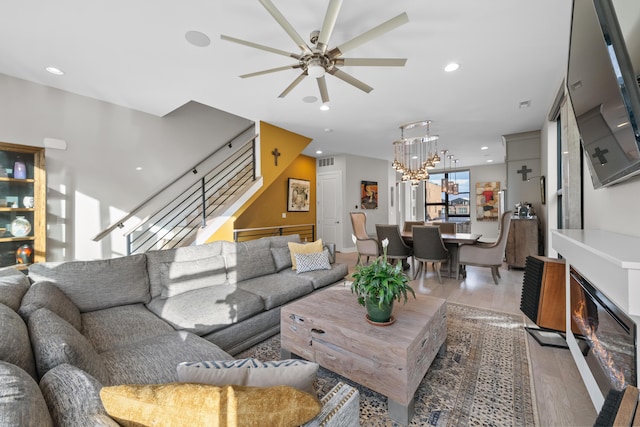 living room with ceiling fan with notable chandelier and light hardwood / wood-style floors