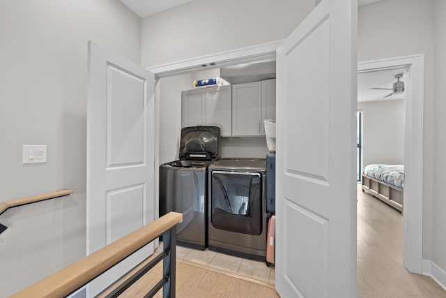 clothes washing area with washing machine and dryer, ceiling fan, cabinets, and light hardwood / wood-style floors