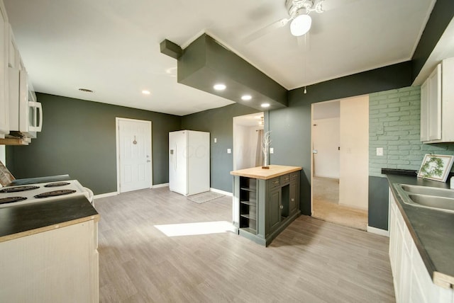 kitchen with white appliances, sink, light hardwood / wood-style flooring, ceiling fan, and white cabinetry