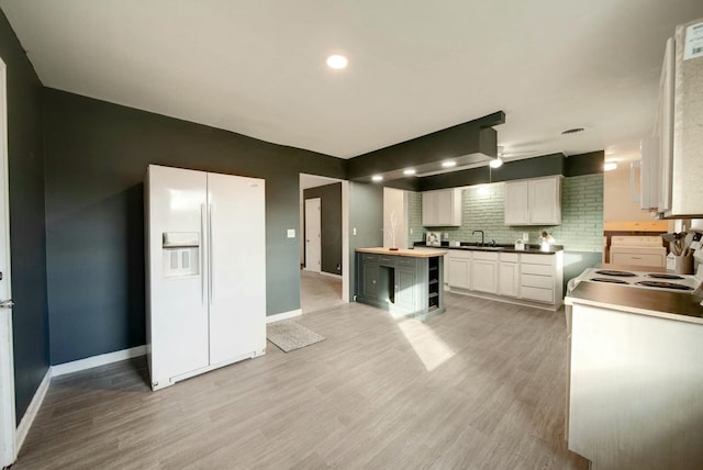 kitchen with white cabinets, sink, white fridge with ice dispenser, tasteful backsplash, and light hardwood / wood-style floors