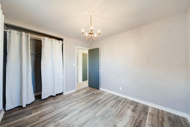 unfurnished bedroom with a chandelier, light wood-type flooring, and a closet