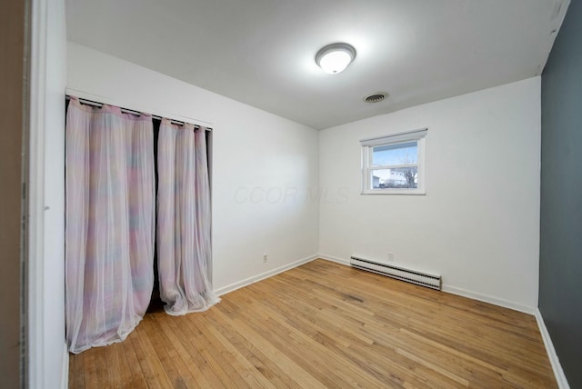 empty room with a baseboard radiator and light hardwood / wood-style floors