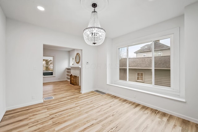 unfurnished dining area featuring an inviting chandelier and light hardwood / wood-style flooring