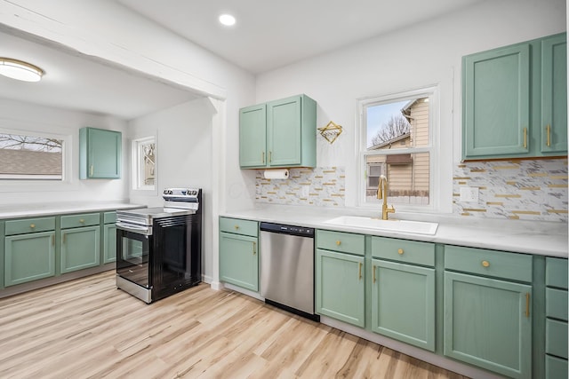 kitchen with sink, stainless steel appliances, light hardwood / wood-style floors, green cabinetry, and decorative backsplash