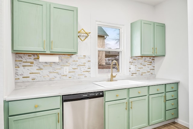 kitchen with stainless steel dishwasher, green cabinets, sink, and backsplash