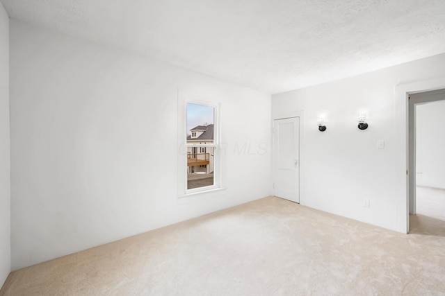 unfurnished room with light colored carpet and a textured ceiling