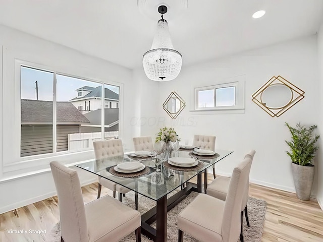 dining area with an inviting chandelier, a healthy amount of sunlight, and light wood-type flooring