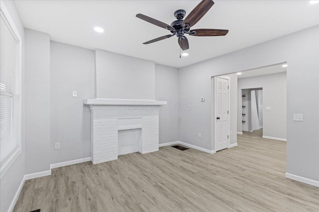 unfurnished living room with ceiling fan, light hardwood / wood-style floors, and a fireplace