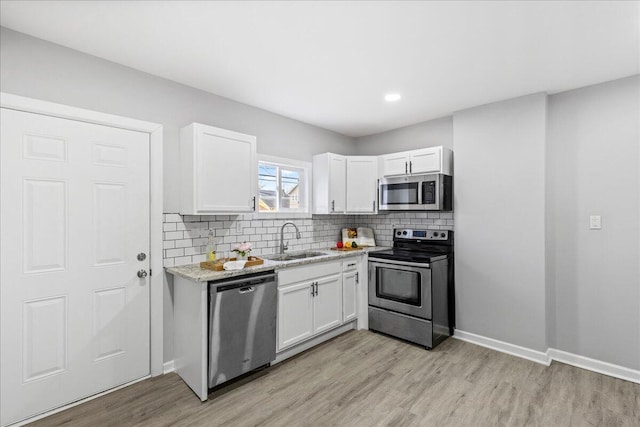 kitchen featuring white cabinetry, sink, stainless steel appliances, and light stone counters