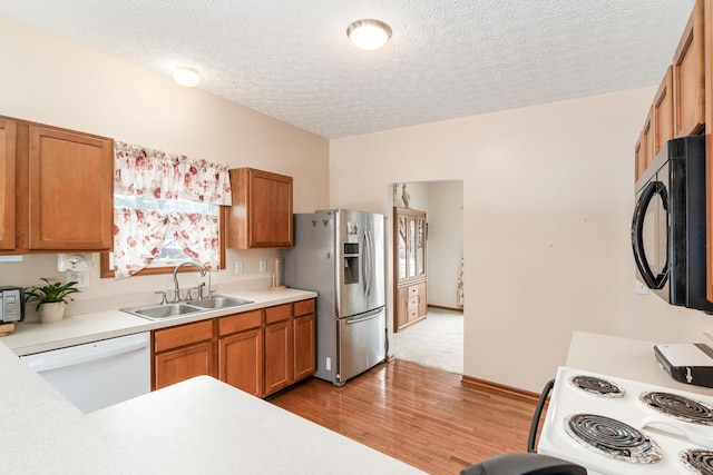 kitchen with dishwasher, sink, stainless steel refrigerator with ice dispenser, a textured ceiling, and light hardwood / wood-style floors