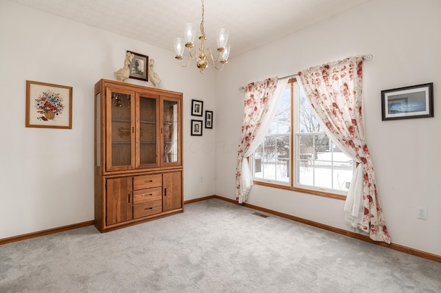 empty room featuring light colored carpet and an inviting chandelier