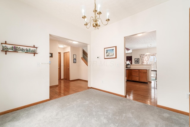 spare room with light carpet, a textured ceiling, and a notable chandelier