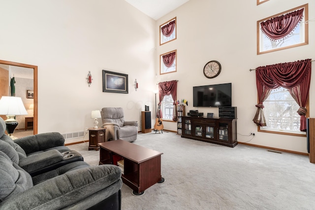 carpeted living room featuring a towering ceiling