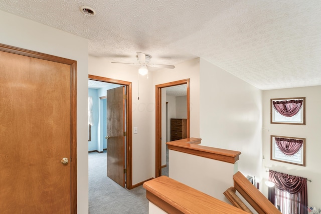 hallway with light carpet and a textured ceiling