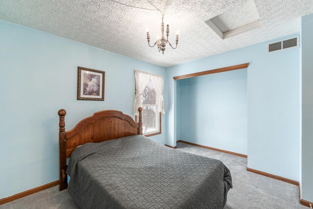 carpeted bedroom with a textured ceiling and a notable chandelier