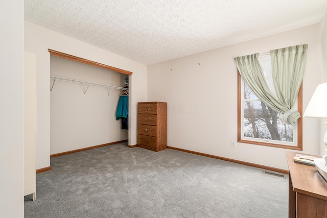 unfurnished bedroom featuring carpet flooring, a textured ceiling, and a closet