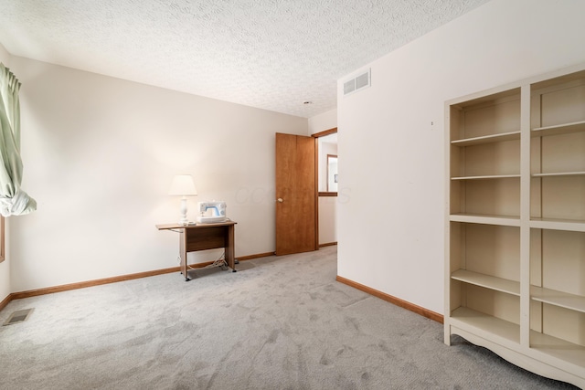 carpeted spare room featuring built in shelves and a textured ceiling